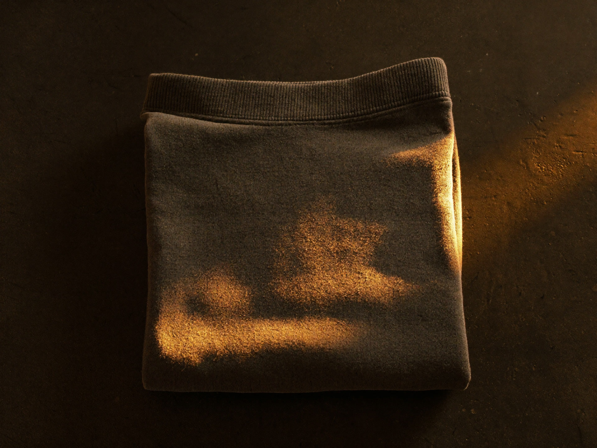 Heavyweight charcoal hoodie folded on dark concrete