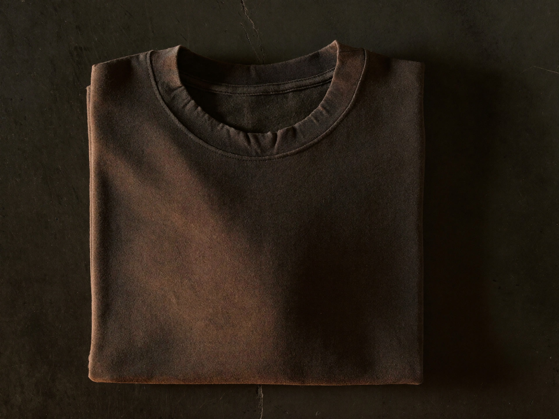 Boxy washed black heavyweight t-shirt folded on dark concrete